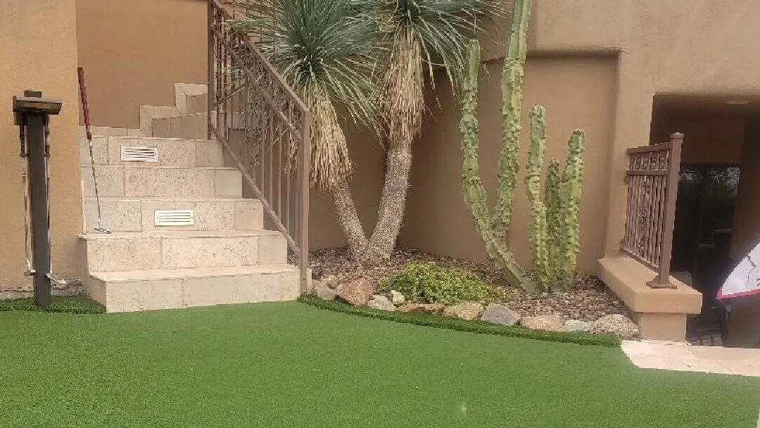 A green lawn next to stairs and bushes.